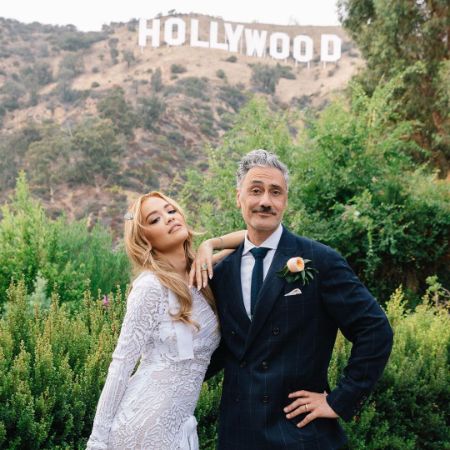 Taika Waititi and Rita Ora are posing with the Hollywood sign in the background.